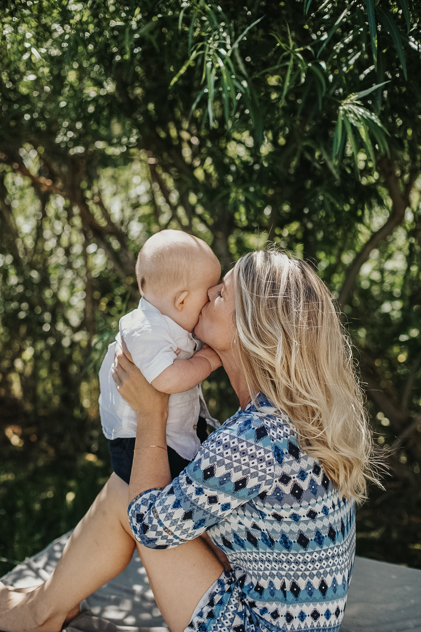 A mother kissing her baby's forehead during an outdoor lifestyle photography session in Bayside, Melbourne.